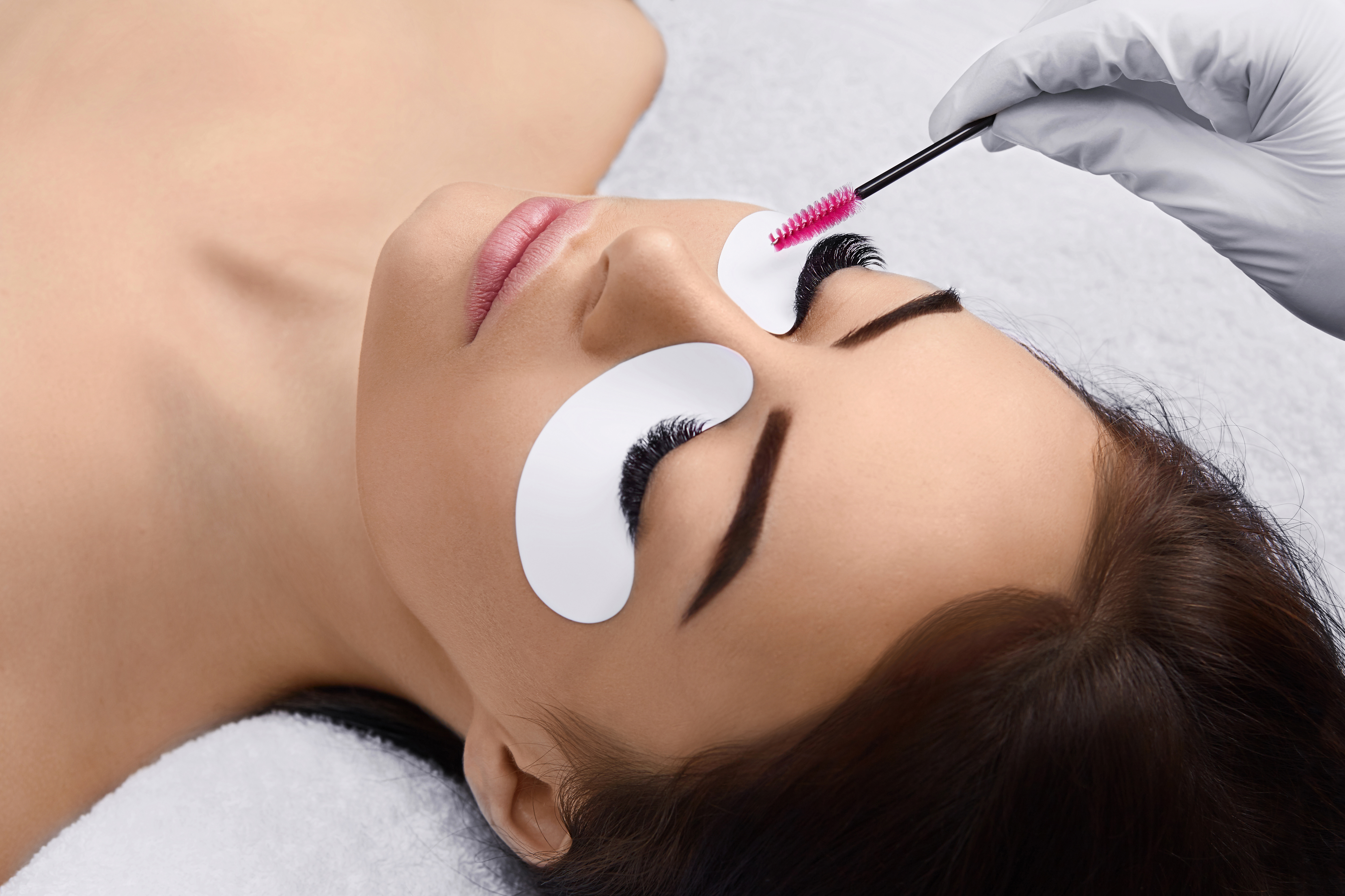 Eyelashes extensions. Fake Eyelashes. Eyelash Extension Procedure. Professional stylist lengthening female lashes. Master and a client in a beauty salon.